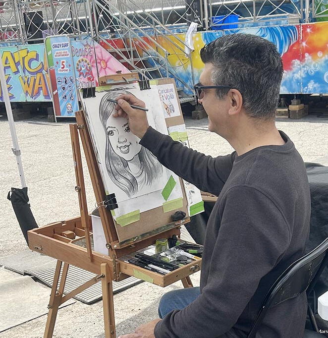 Caricature artist sketching a guest at an amusement fair